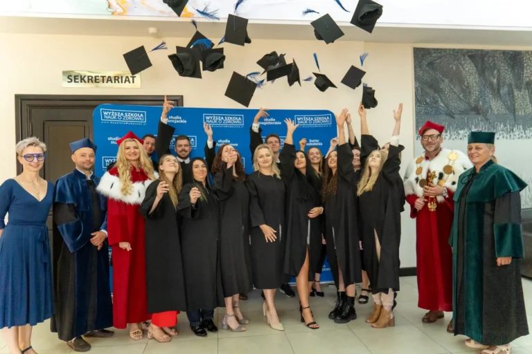 Na zdjęciu widać grupę studentów fizjoterapii z Wyższej Szkoły Nauk o Zdrowiu w strojach akademickich rzucających czapkami absolwenckimi w powietrze.